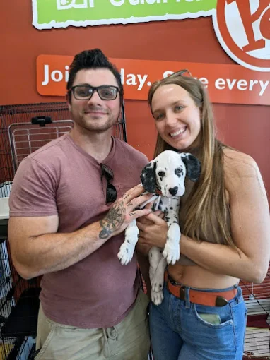 Two adults welcoming a spotted puppy at Petland