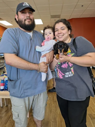 A family holding a puppy together at Petland